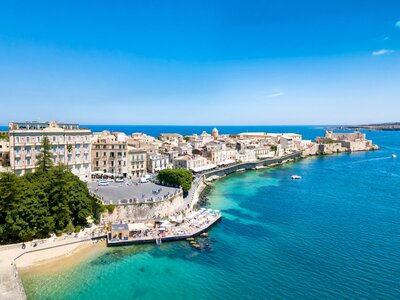 distant panoramic view of Ortigia with turquoise waters surrounding, Syracuse, Italy